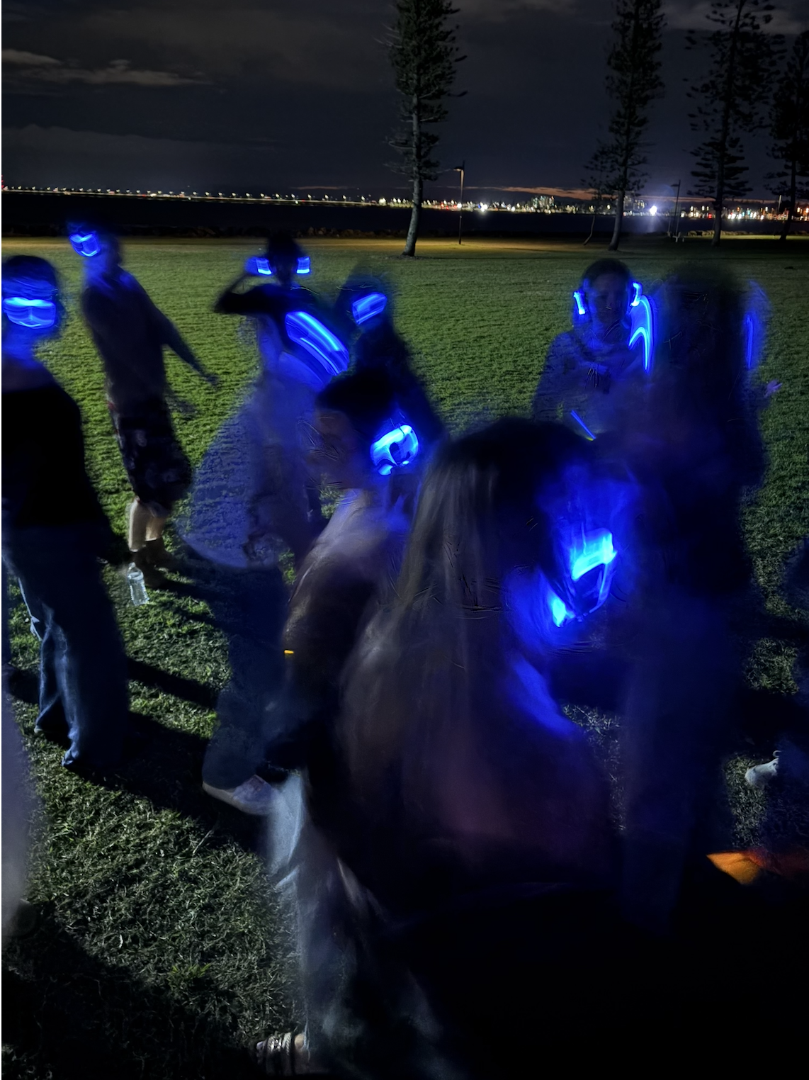 Blue glowing headphones lighting up a night time silent disco by the water